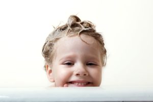 Child with wet hair smiling behind blog